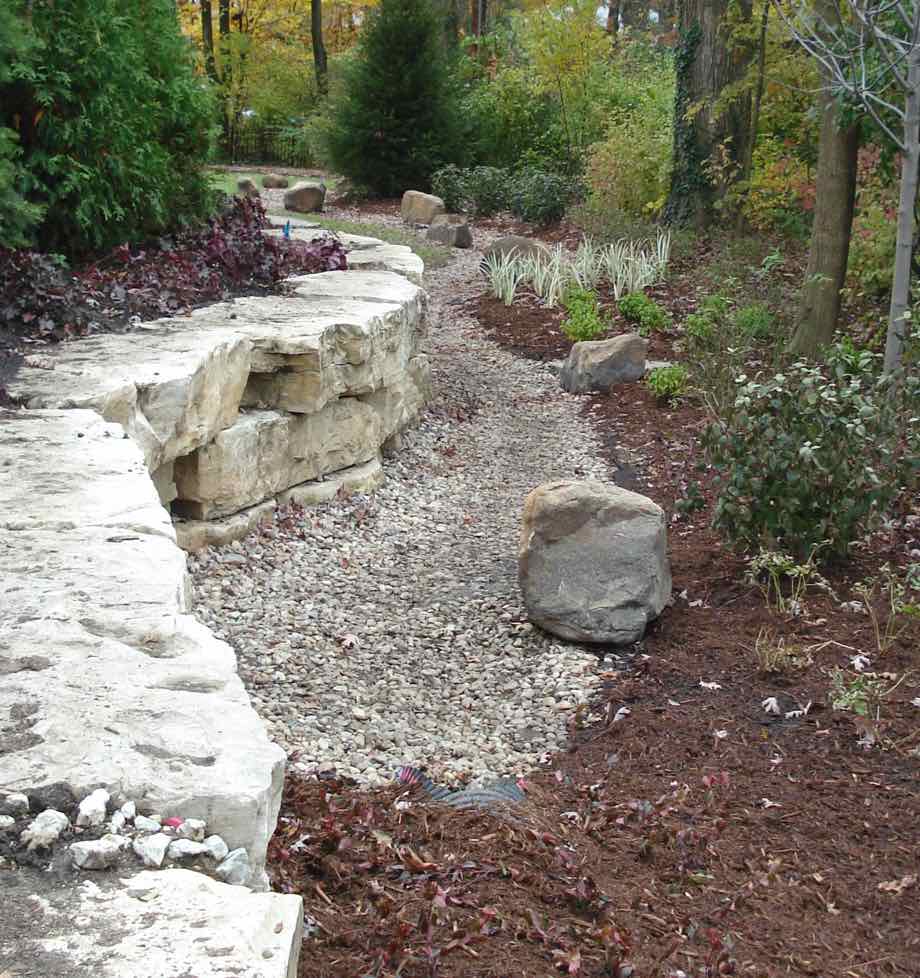 Rock wall with covered landscaped drainage